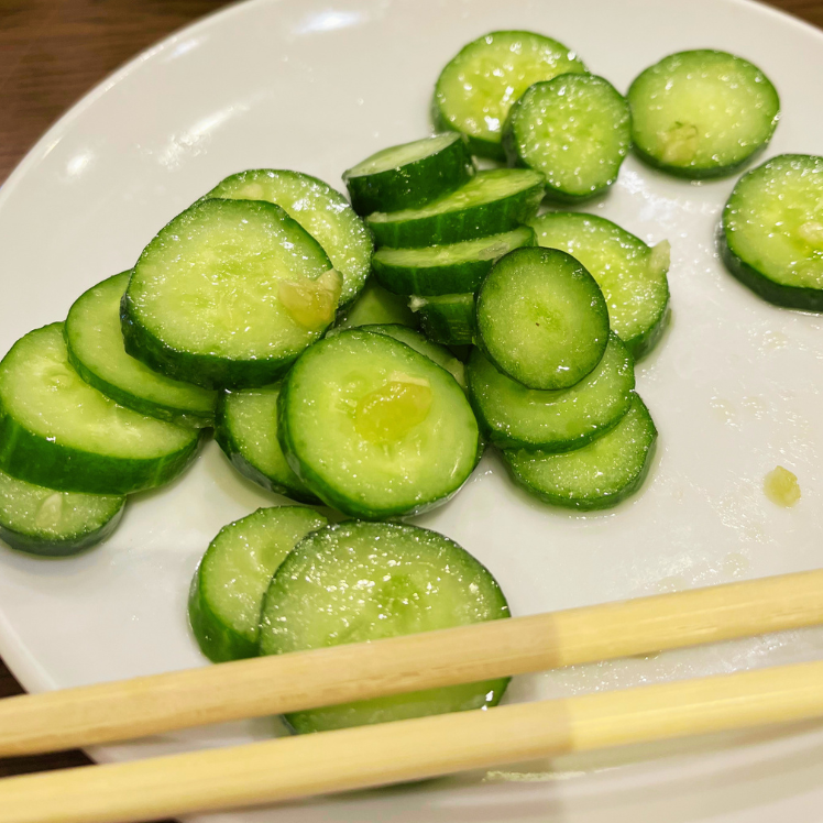 白いお皿に盛った、薄切りのきゅうりの和え物と、添えられた箸